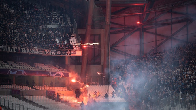 Pyrotechnik fliegt zwischen den Fan-Blöcken beider Klubs hin und her.