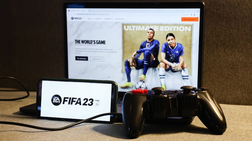 Am 27. September 2022 erscheint die neue Version des Konsolen-Klassikers FIFA. Auf dem Foto ist das Logo des neuen Teils auf einem Smartphone zu sehen, im Hintergrund zeigt ein Laptop das voraussichtliche Cover.