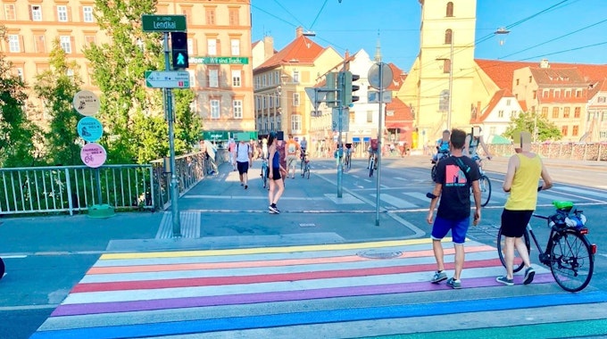 Ein Zebrastreifen in Regenbogenfarben führt über eine Straße.