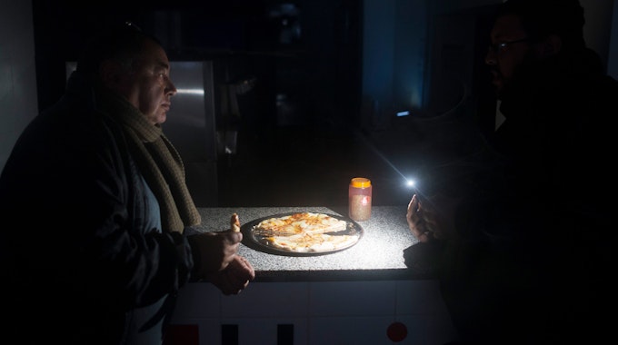 Zwei Männer sitzen in einem Restaurant in Buenos Aires und essen im Schein ihrer Taschenlampen Pizza. Der Stromausfall am 16. Juni 2019 war der größte in der Geschichte des südamerikanischen Landes.