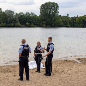 Rettungskräfte und Polizei stehen an einem See und besprechen den weiteren Einsatz.