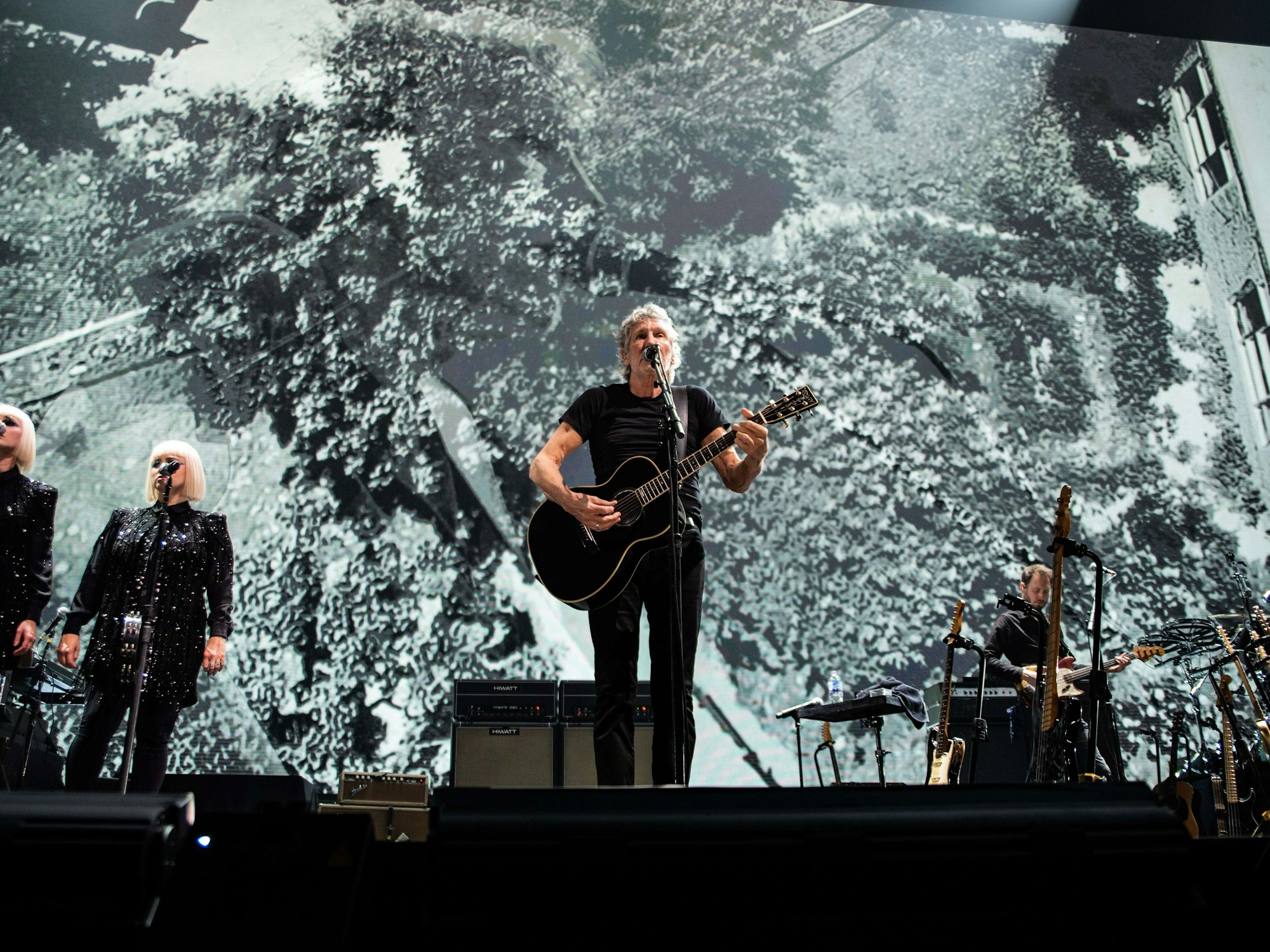 Roger Waters steht mit Gitarre auf der Bühne in Glasgow und singt bei einem Konzert.