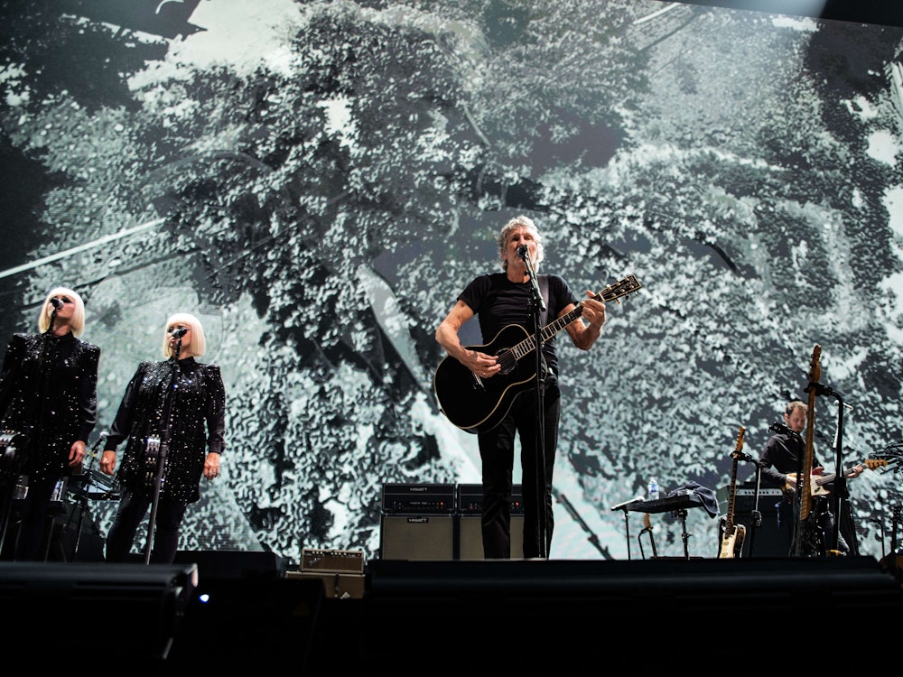Roger Waters steht mit Gitarre auf der Bühne in Glasgow und singt bei einem Konzert.