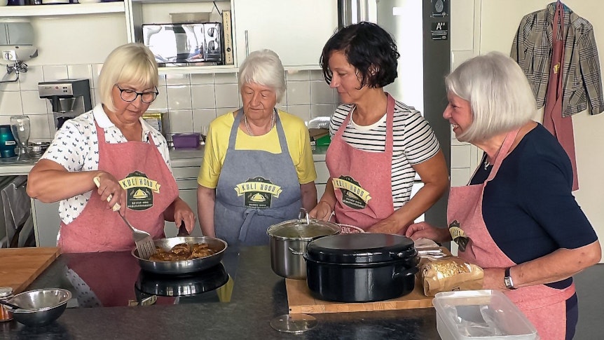 Marion Reiners steht mit drei Seniorinnen in der Küche um den Herd.