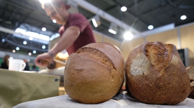Ein Bäcker zeigt sein Können auf der Messe Agra 2022, während im Vordergrund Brote liegen.