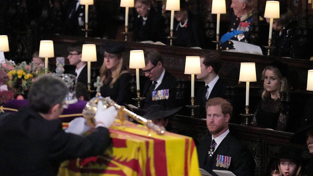 Prinz Harry, (vorne l-r), Herzog von Sussex, Prinzessin Charlotte, Kate, Prinzessin von Wales und Prinz George sehen zu, wie die Krone, der Reichsapfel und das Zepter während der Beisetzung in der St.-Georges-Kapelle auf Schloss Windsor vom Sarg von Königin Elizabeth II. abgenommen werden.