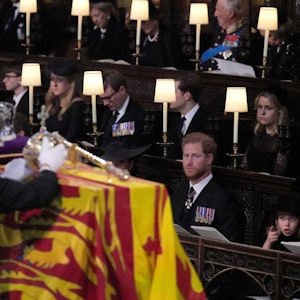 Prinz Harry, (vorne l-r), Herzog von Sussex, Prinzessin Charlotte, Kate, Prinzessin von Wales und Prinz George sehen zu, wie die Krone, der Reichsapfel und das Zepter während der Beisetzung in der St.-Georges-Kapelle auf Schloss Windsor vom Sarg von Königin Elizabeth II. abgenommen werden.