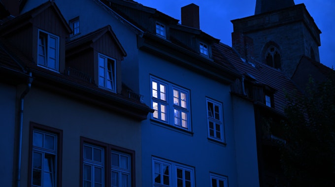 Dieses undatierte Symbolbild zeigt ein hell erleuchtetes Wohnungsfenster im Morgengrauen.