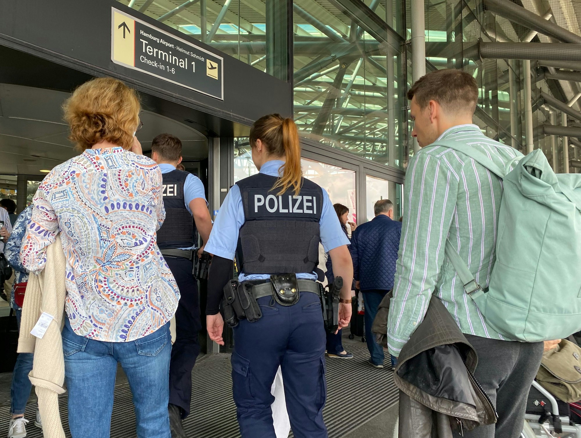 Passagiere und Polizisten und Polizistinnen betreten den Flughafen. Die Aufnahme vom 1. Juni 2022 dient hier als Symbolfoto.