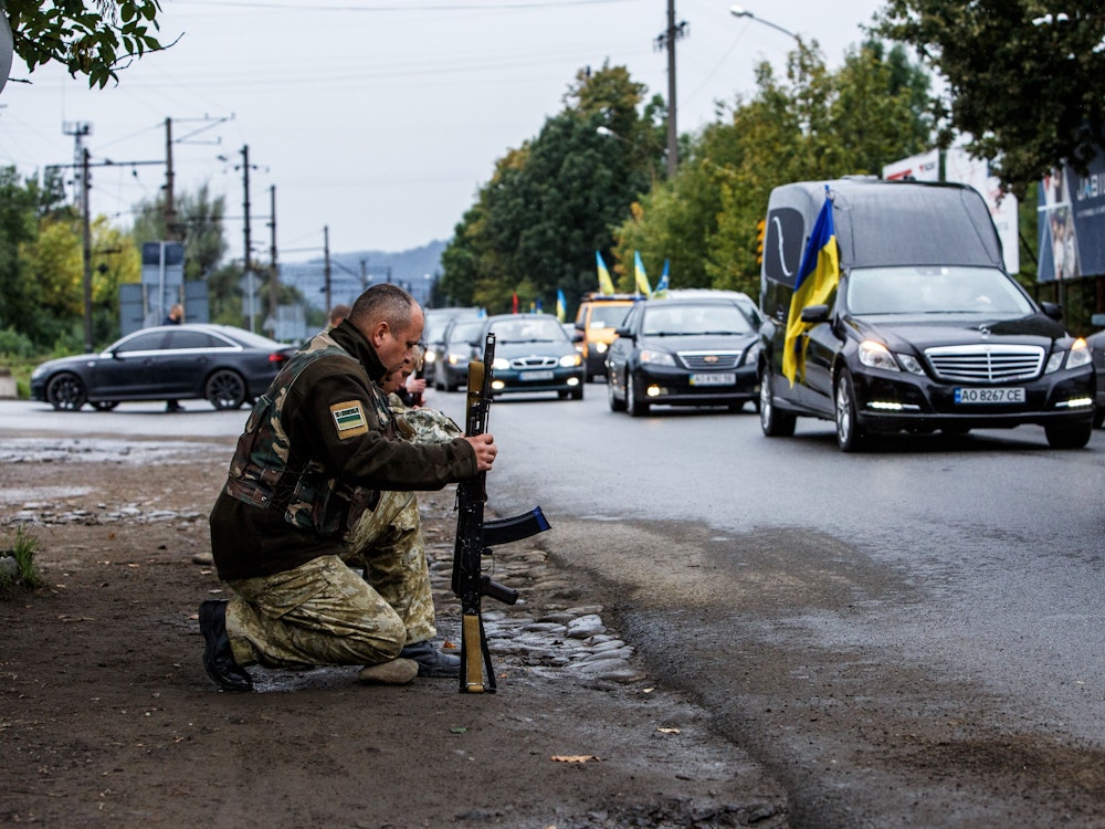 Soldaten knien mit ihren Waffen am Rand einer Straße, um Oberleutnant Armen Petrosian zu gedenken, der bei der Befreiung der nordöstlichen Region Charkiw von den russischen Besatzungstruppen ums Leben kam, während ein Autokonvoi mit seinem Sarg vorbeifährt.