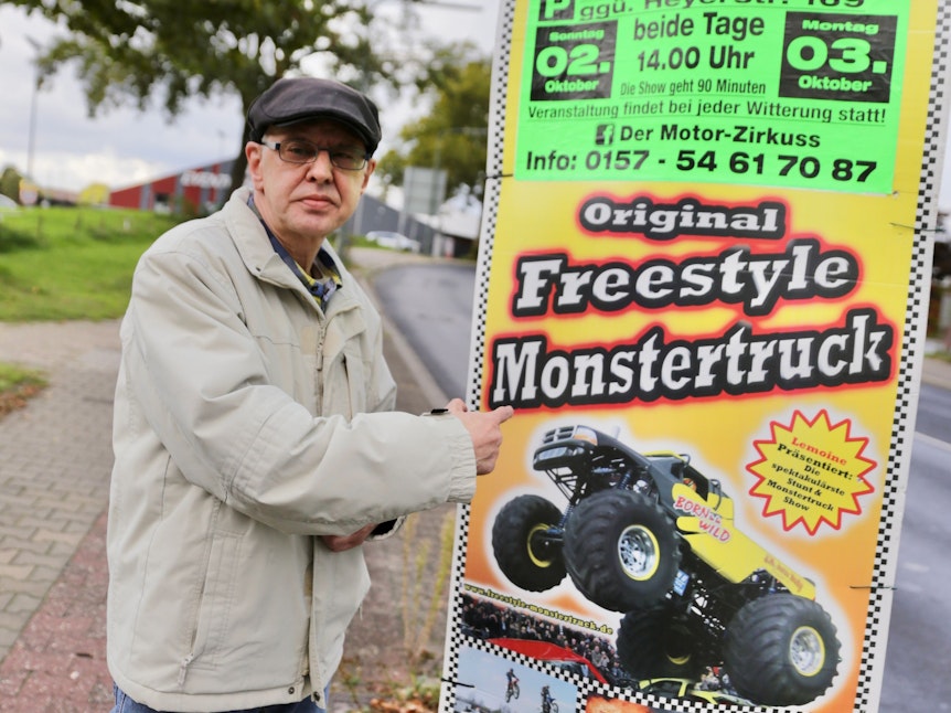 Tony Marony steht neben einem Plakat, das eine Monster Truck-Show ankündigt.