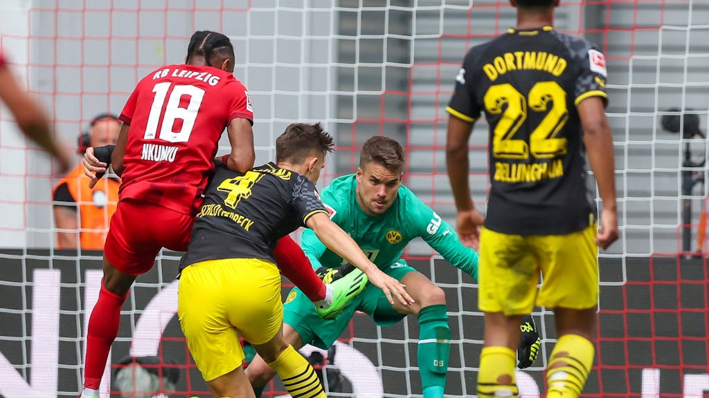 Dortmunds Torwart Alexander Meyer (2.v.r) und Nico Schlotterbeck klären gegen Leipzigs Christopher Nkunku (l). 