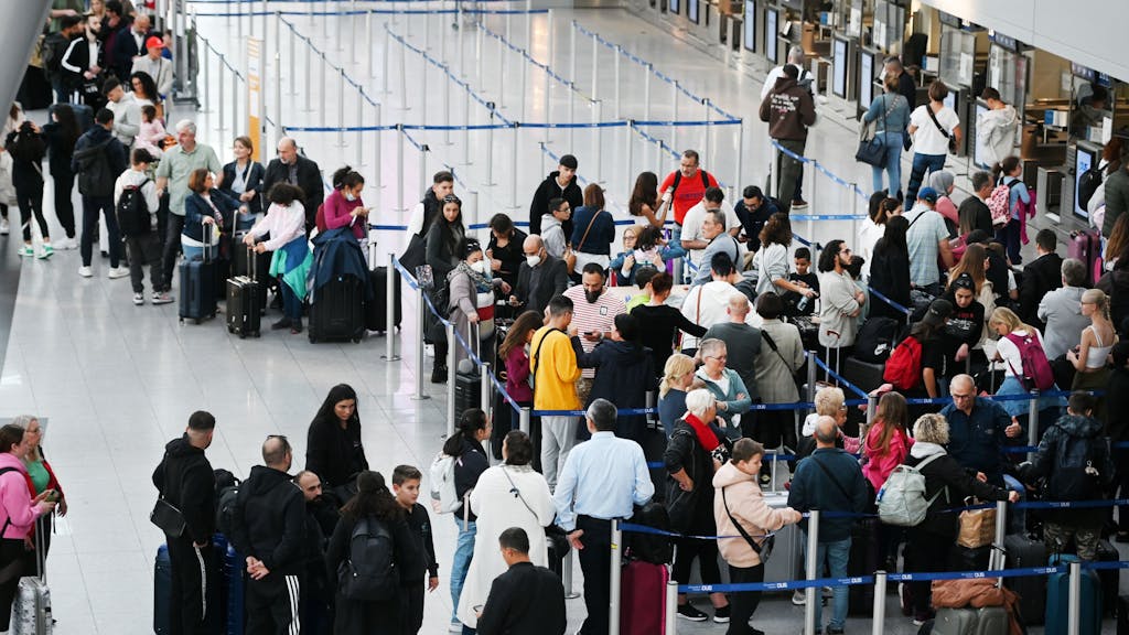 Reisende des Düsseldorfer Flughafens stehen in der Abflugshalle an den Schaltern in Schlangen.