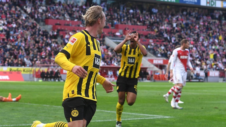 Julian Brandt (v.) feiert sein Tor zum 1:0 für Borussia Dortmund beim 1. FC Köln, Jude Bellingham zelebriert die Führung mit dem Modeste-Jubel.