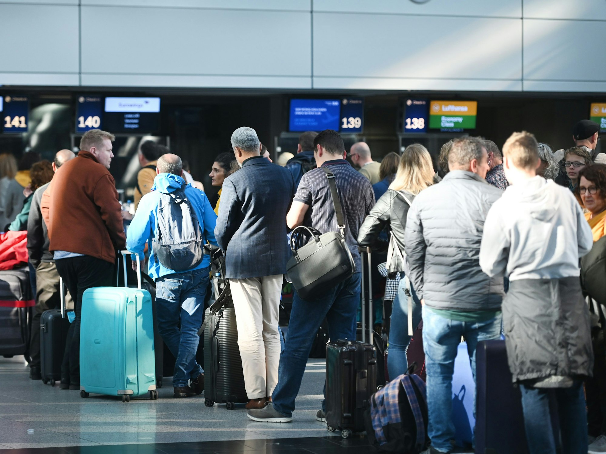 Reisende des Düsseldorfer Flughafens stehen in der Abflughalle an den Schaltern in Schlangen.