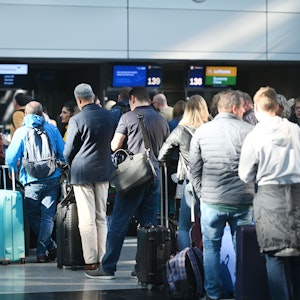 Reisende des Düsseldorfer Flughafens stehen in der Abflughalle an den Schaltern in Schlangen.