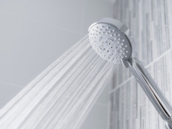 Ein Sparduschkopf sprüht Wasser in einer Dusche