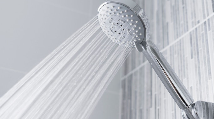 Ein Sparduschkopf sprüht Wasser in einer Dusche