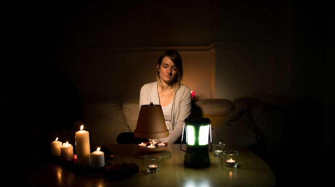 Eine junge Frau beleuchtet ihre Wohnung während eines Stromausfalls mit Kerzen