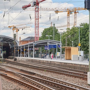 Hinter dem ersten Gleis des Bonner Hauptbahnhofs sind Baukräne zu sehen.