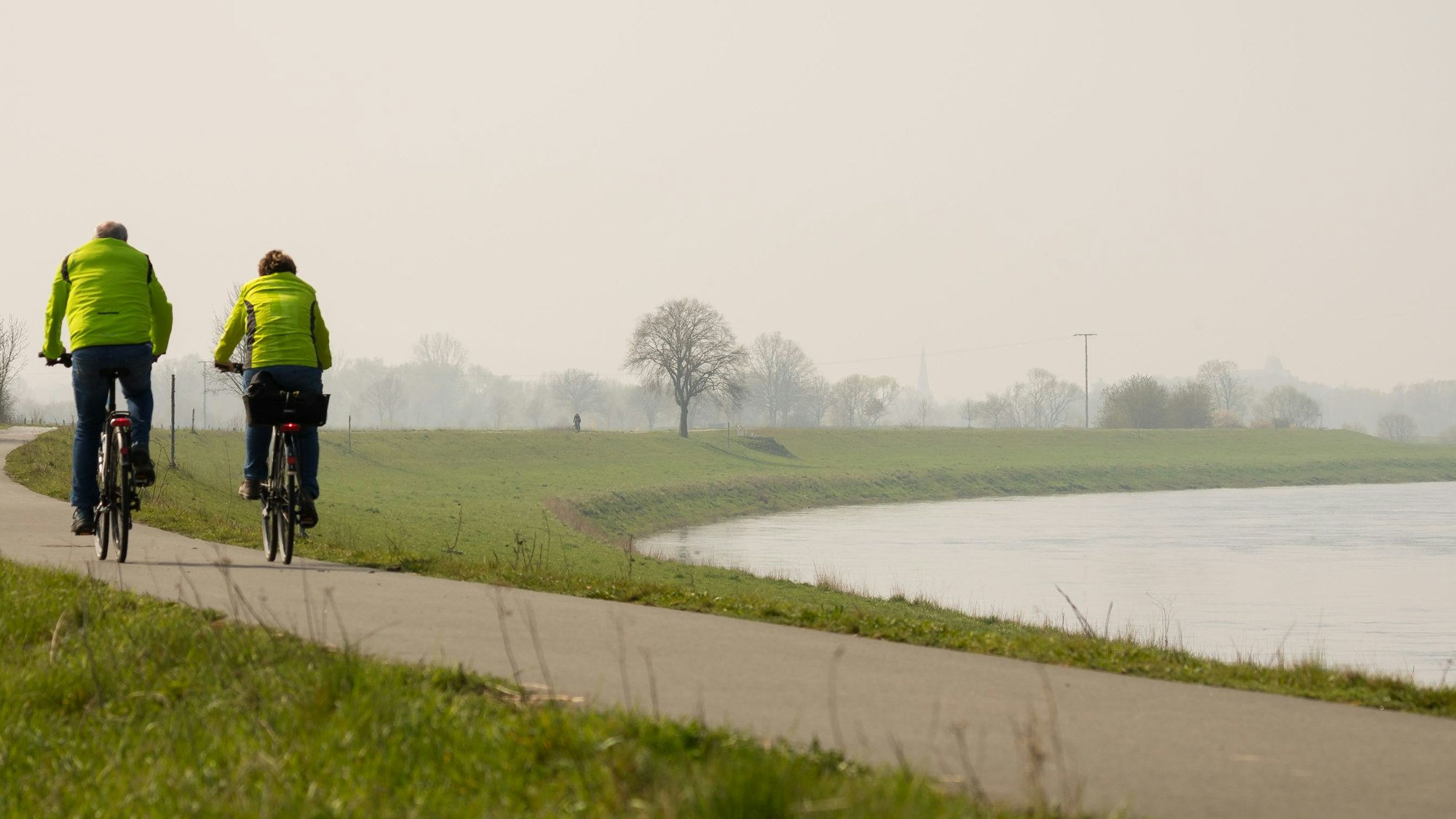 Ein Fahrradfahrer und eine Fahrradfahrerin fahren auf dem Weser-Radweg bei Höxter.