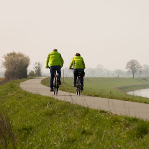 Ein Fahrradfahrer und eine Fahrradfahrerin fahren auf dem Weser-Radweg bei Höxter.