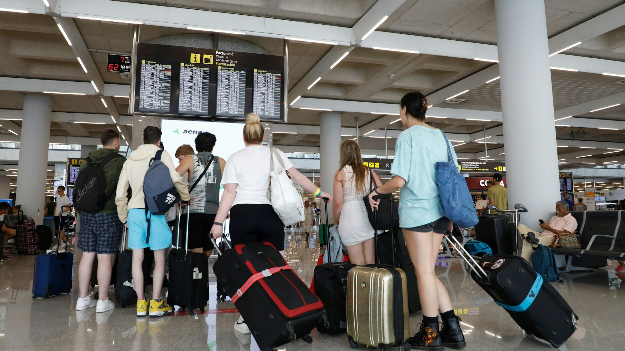 Reisende schauen am Flughafen auf die Anzeigetafel mit den Flugzeiten.