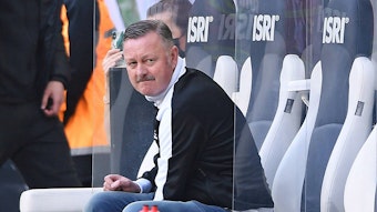 Ein enttäuschter Blick: Gladbach-Manager Roland Virkus sitzt bei der Derby-Niederlage gegen den 1. FC Köln am 16. April 2022 auf der Spielerbank im Borussia-Park. Virkus trägt eine schwarz-weiße Puma-Jacke.
