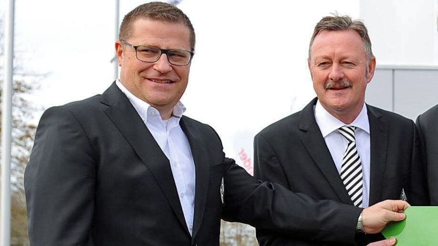 Gladbach-Manager Roland Virkus (r.) mit seinem Amts-Vorgänger Max Eberl (l.). Dieses Foto zeigt die beiden am 12. März 2019 bei einem Pressetermin im Borussia-Park. Virkus und Eberl lächeln in die Kamera.
