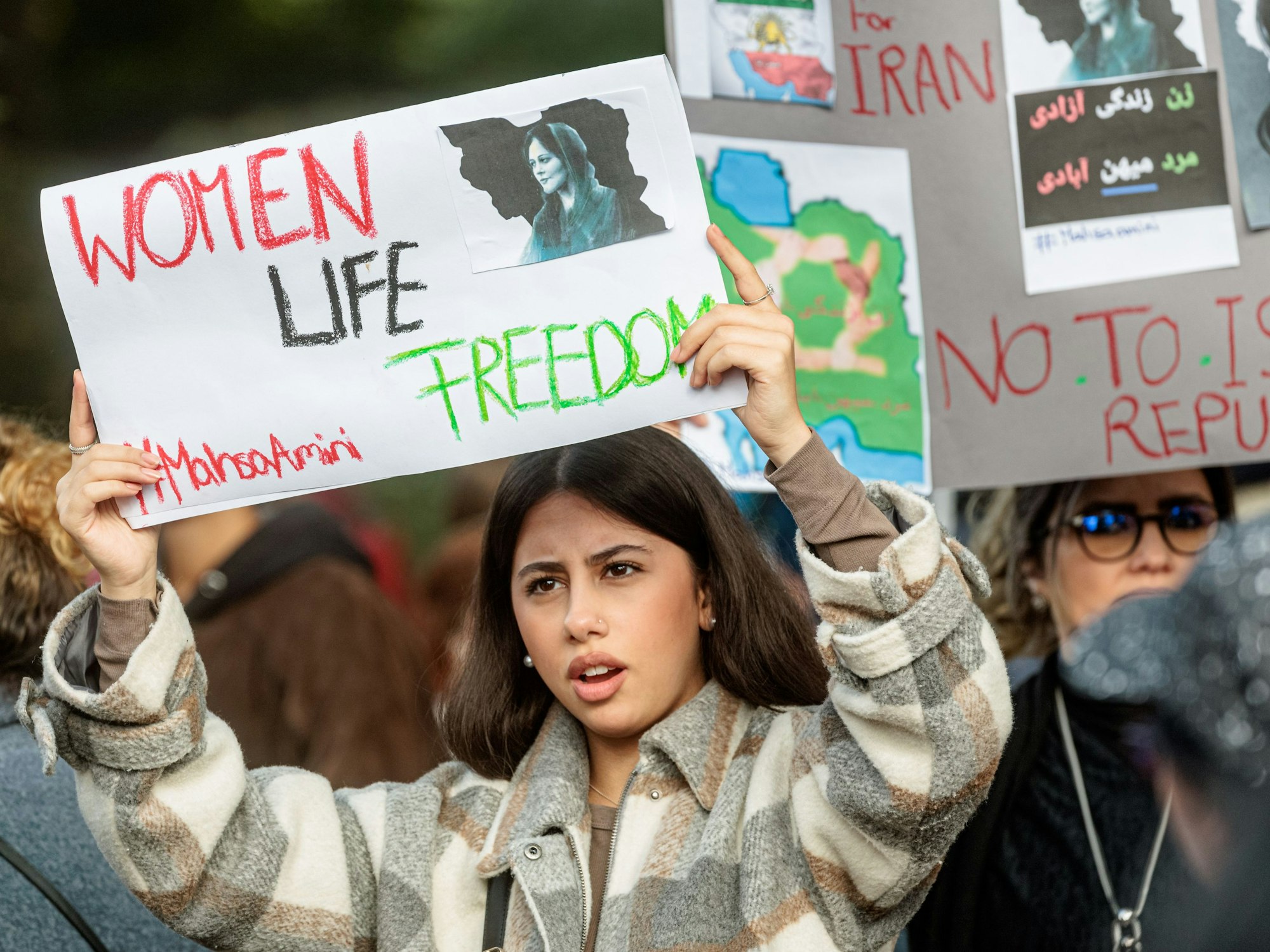 Eine Frau hält ein Schild mit der Aufschrift „Women, Life, Freedom“, dem aktuellen internationalen Slogan gegen das Mullah-Regime in Iran, hoch.