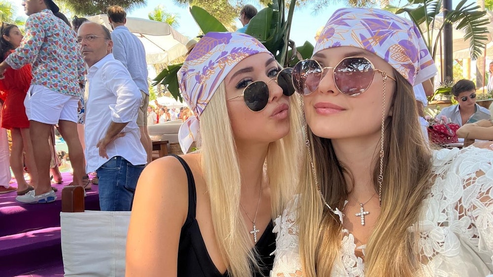 Shania und Davina posieren mit pinken Kopftüchern und Sonnenbrillen für ein Selfie.