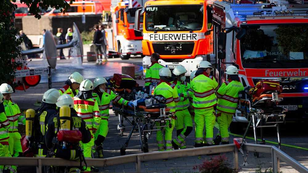 Rettungskräfte stehen am Samstag (8. Oktober 2022) während der Löscharbeiten am U-Bahnhof Ebertplatz in Köln.