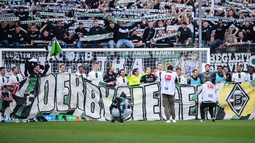 Die Spieler von Fußball-Bundesligist Borussia Mönchengladbach feiern den Derbysieg (9. Oktober 2022) gegen den 1. FC Köln im Borussia. Allerdings plagen die Elf vom Niederrhein im Anschluss Personalsorgen. Zu sehen ist ein Banner mit dem Aufdruck Derbysieger.
