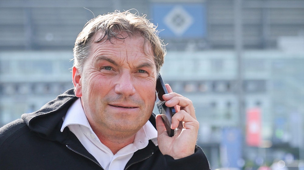 Thomas Wüstefeld telefoniert vor dem Spiel auf dem Parkplatz vor dem Stadion.