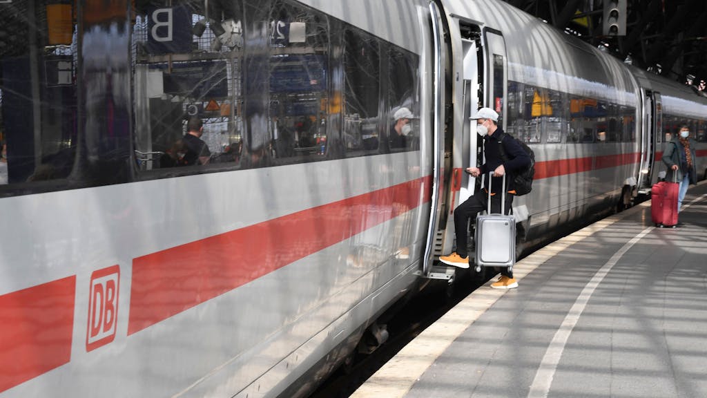 Ein Mann steigt am Hauptbahnhof in Köln mit Koffer in einen ICE.