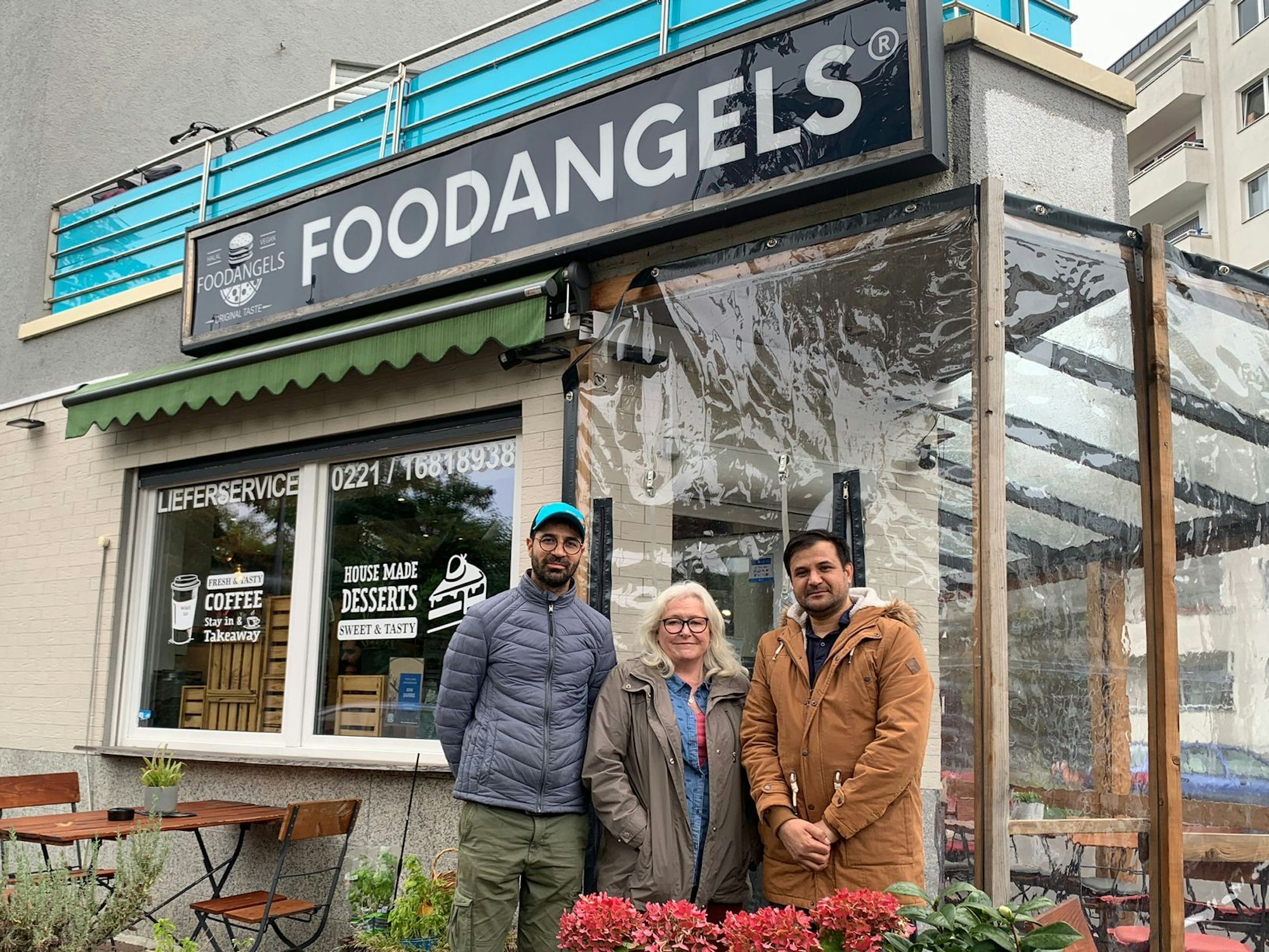 Inhaber Mazlom Sediqi, Unterstützerin Susanne Zeltinger und Fazal Rabi Rahimzai stehen vor dem Foodangels-Bistro auf der Kölner Etzelstraße.