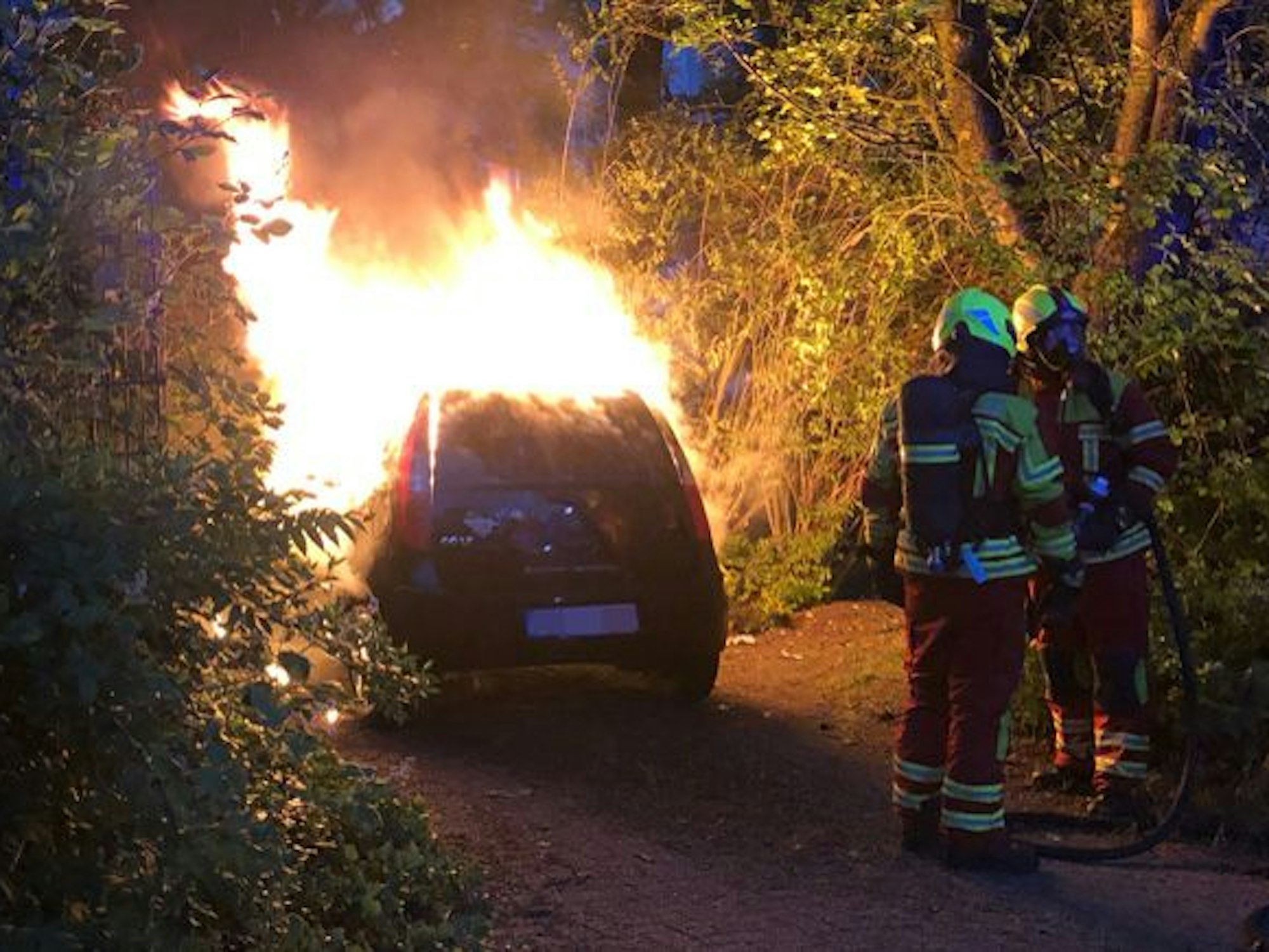 Die Feuerwehr löscht ein brennendes Auto.