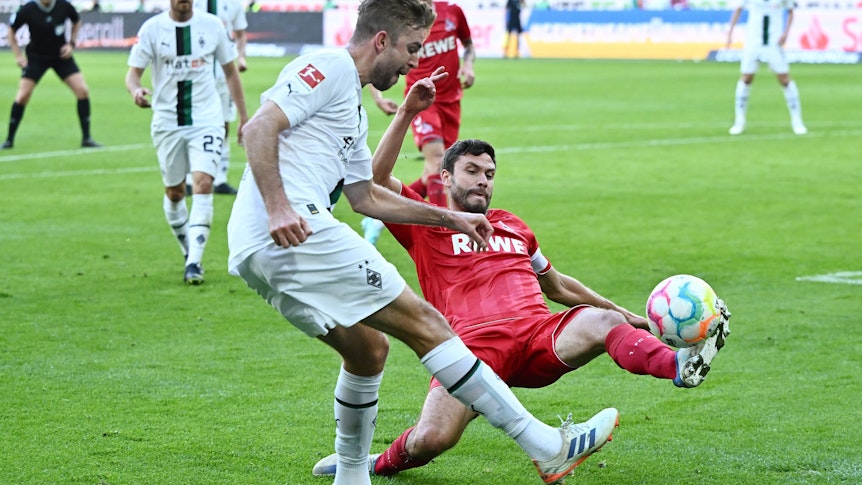 Christoph Kramer von Borussia Mönchengladbach schlägt eine Flanke im Derby gegen den 1. FC Köln am 9. Oktober 2022, Gegenspieler Jonas Hector will das verhindern.