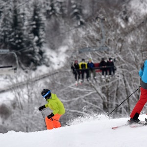 Das Symbolfoto zeigt zwei Personen mit Ski-Ausrüstung, die einen schneebedeckten Abhang hinunterfahren.