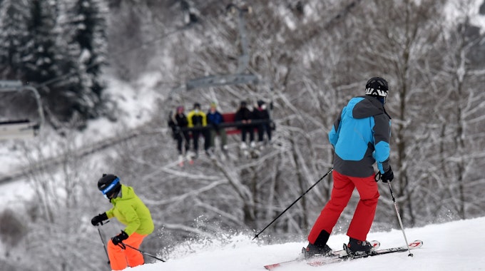 Das Symbolfoto zeigt zwei Personen mit Ski-Ausrüstung, die einen schneebedeckten Abhang hinunterfahren.