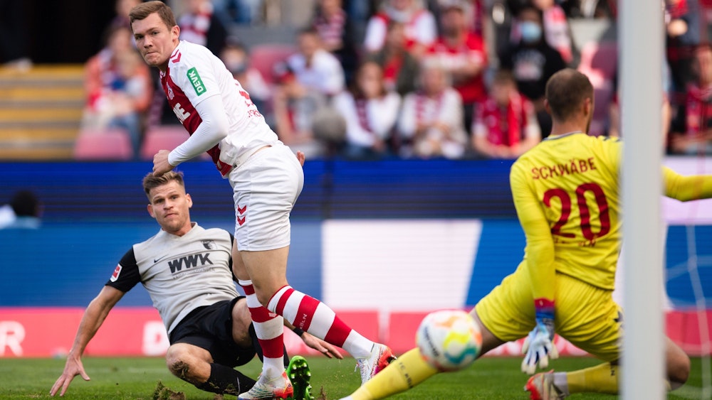 Augsburgs Florian Niederlechner trifft gegen Kölns Luca Kilian und Torhüter Marvin Schwäbe zur 1:0 Führung.