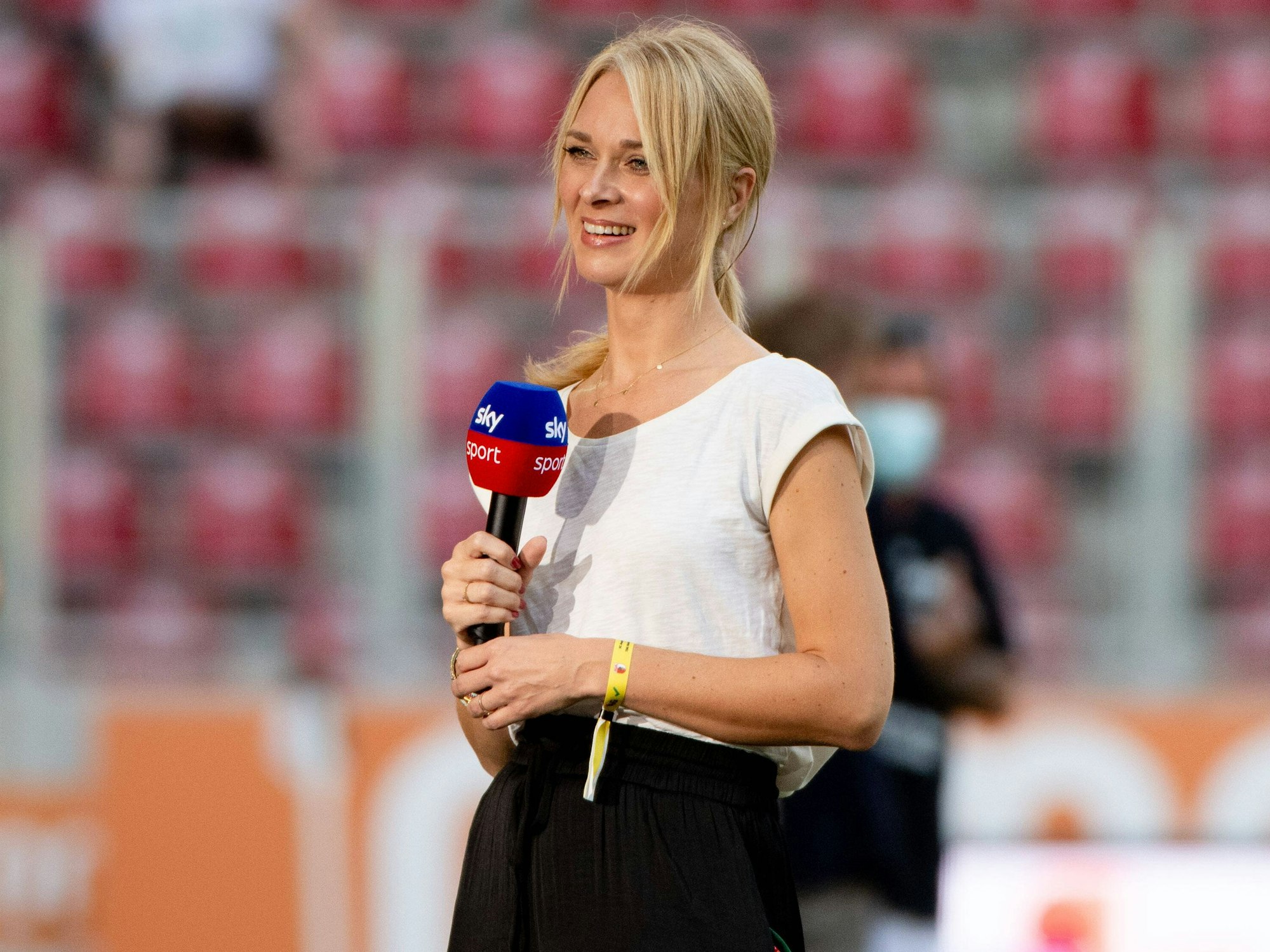 Moderatorin Britta Hofmann steht mit Sky-Mikrofon am Spielfeldrand.
