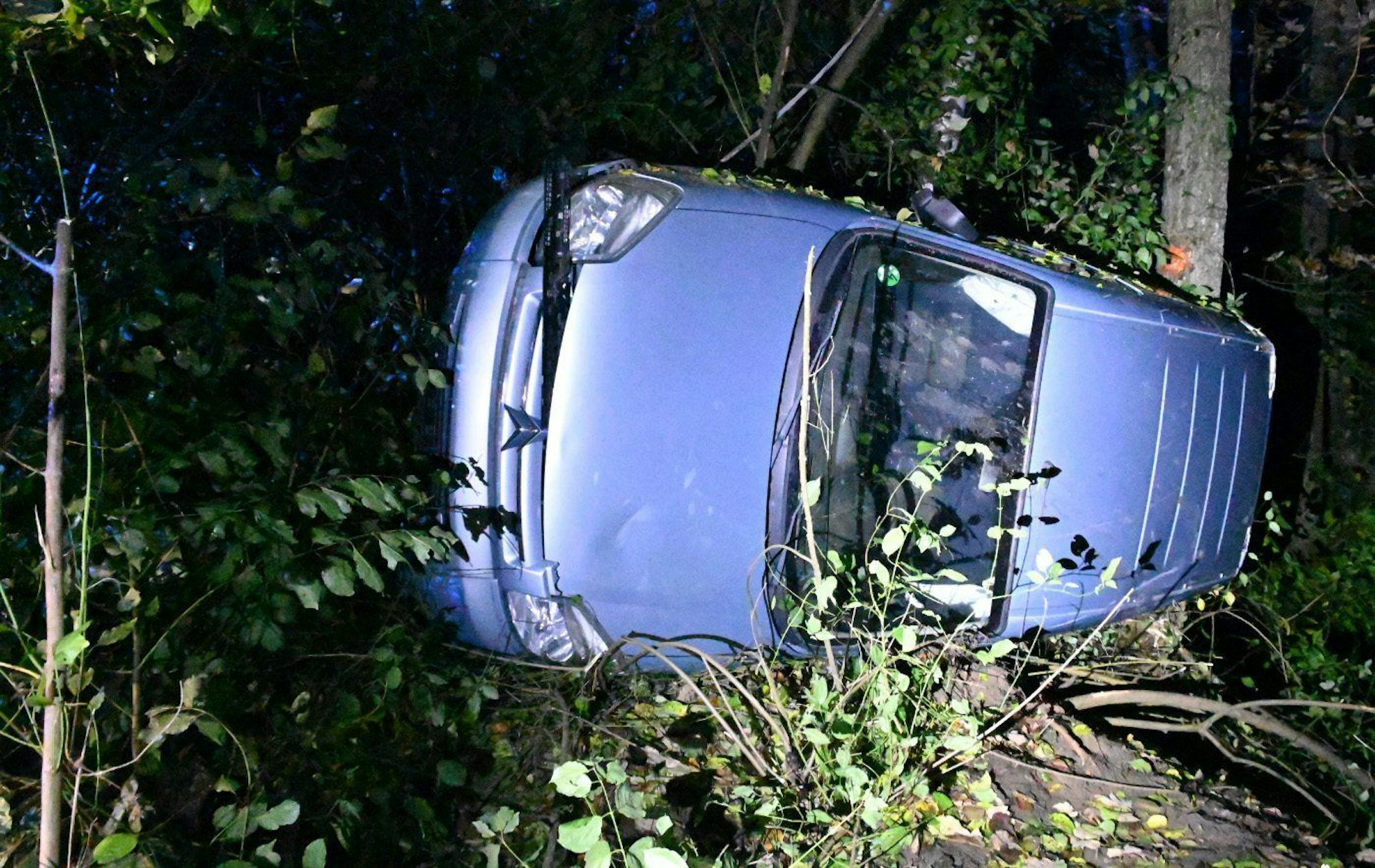 Das gestohlene Auto hängt nach einem Unfall an einem Baum.