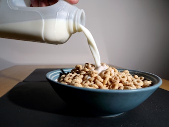 Milch wird in eine Schüssel mit Frühstückscerealien gegossen.