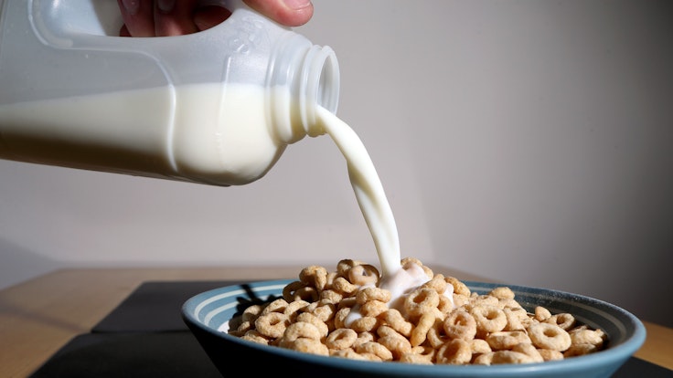 Milch wird in eine Schüssel mit Frühstückscerealien gegossen.