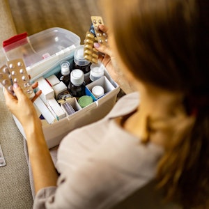 Person hat Tabletten in der Hand. Box mit Medikamenten und Verbandszeug. Bild für Amazon-Artikel.