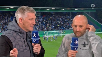 Weltmeister und ARD-Experte Bastian Schweinsteiger (l.) im Gespräch mit Darmstadt-Trainer Torsten Lieberknecht nach dem DFB-Pokal-Spiel der Lilien gegen Borussia Mönchengladbach am 18. Oktober 2022. Beide halten jeweils ein Mikrofon in der Hand.
