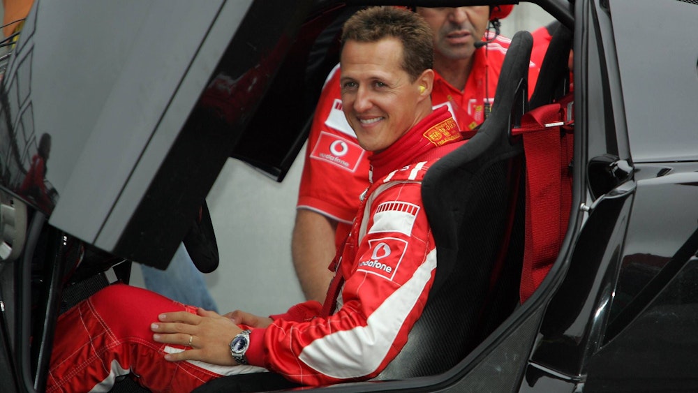 Michael Schumacher sitzt lächelnd im Ferrari