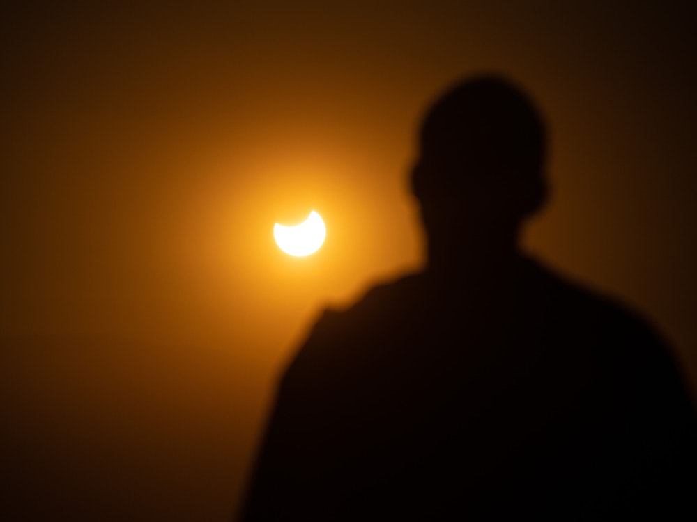 Mann schaut aus der Ferne einer partiellen Sonnenfinsternis zu. In Europa wird die Sonne am Dienstag etwa zu 20 bis 30 Prozent verdeckt sein.