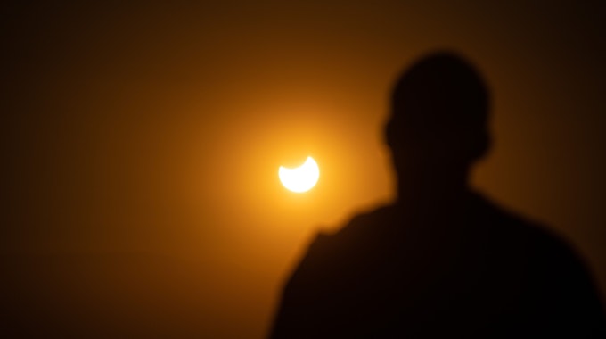 Mann schaut aus der Ferne einer partiellen Sonnenfinsternis zu. In Europa wird die Sonne am Dienstag etwa zu 20 bis 30 Prozent verdeckt sein.